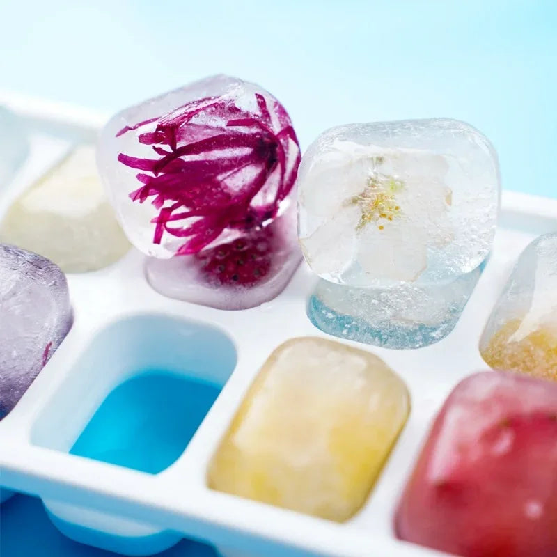 Ice cube tray with colorful ice cubes containing flowers and plants.