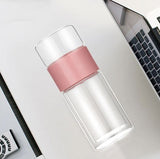 Clear water bottle with pink cap on a desk next to a laptop