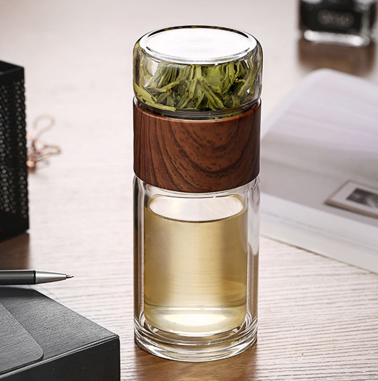 Clear glass tea infuser with wooden sleeve on a desk